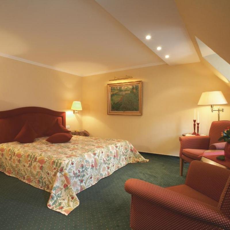 Zimmer 26: großes Zimmer mit Doppelbett, 2 roten Sesseln und Couchtisch
